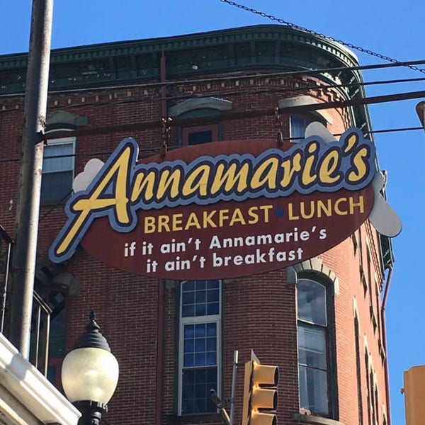 Annamarie's Place restaurant sign, a red oval with yellow lettering, on a brick building.