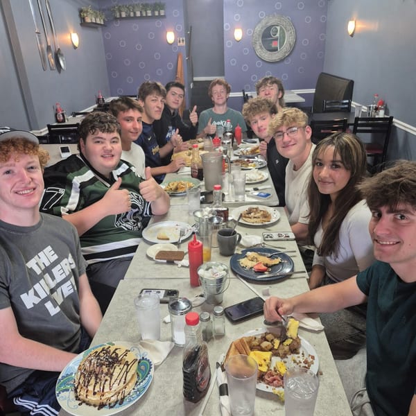 A group of young people enjoying breakfast at Annamarie's Place, with pancakes and other dishes.