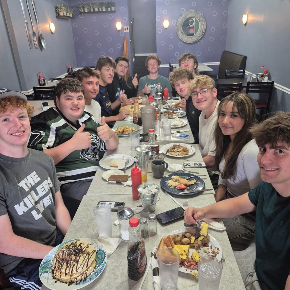 A group of young people enjoying breakfast at Annamarie's Place, with pancakes and other dishes.