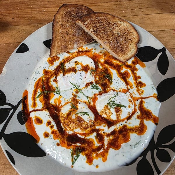Annamarie's Place's poached eggs with yogurt, chili oil, dill, and toast on a decorative plate.